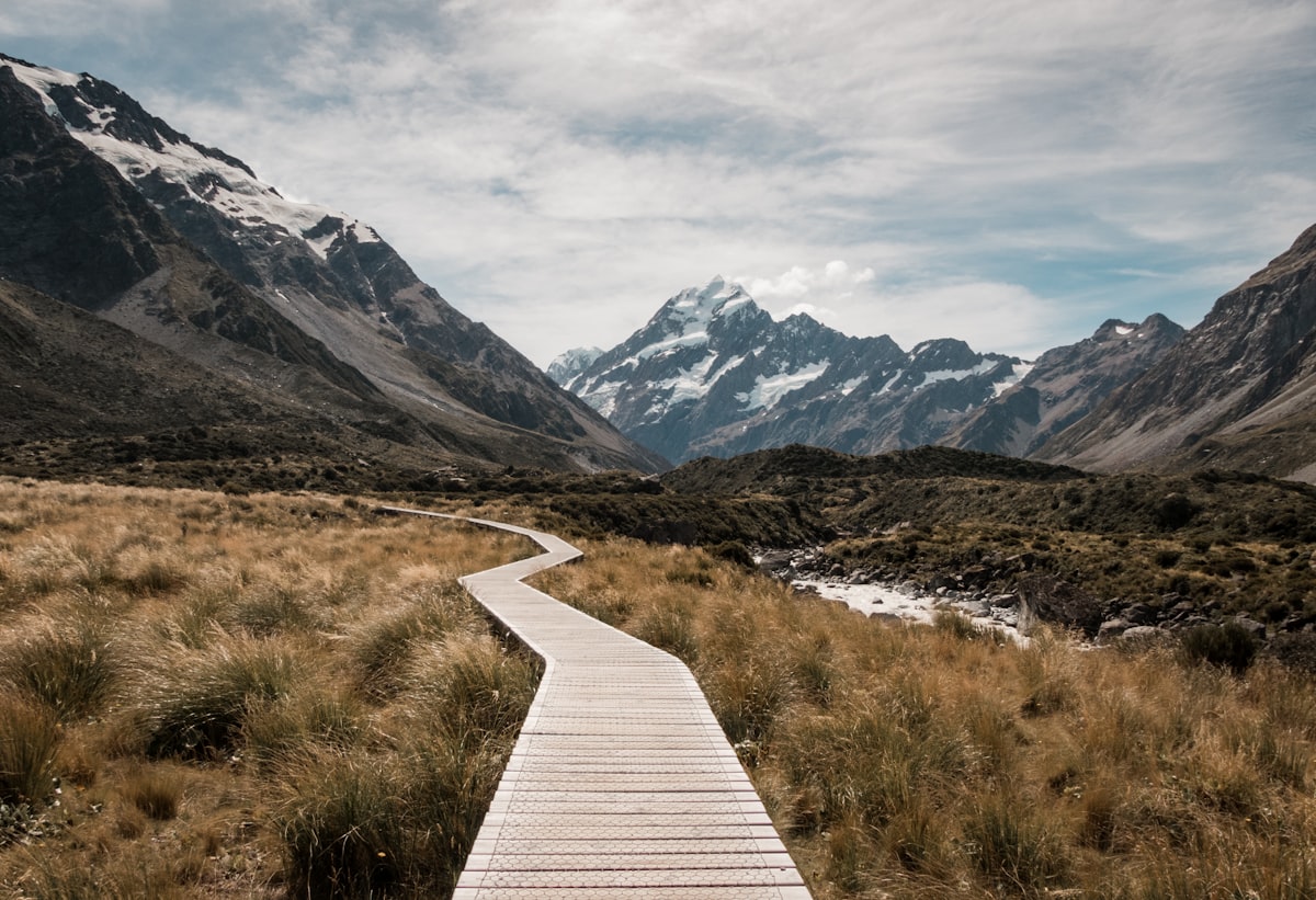 Boardwalk leading to snow-capped mountains — journey and destination